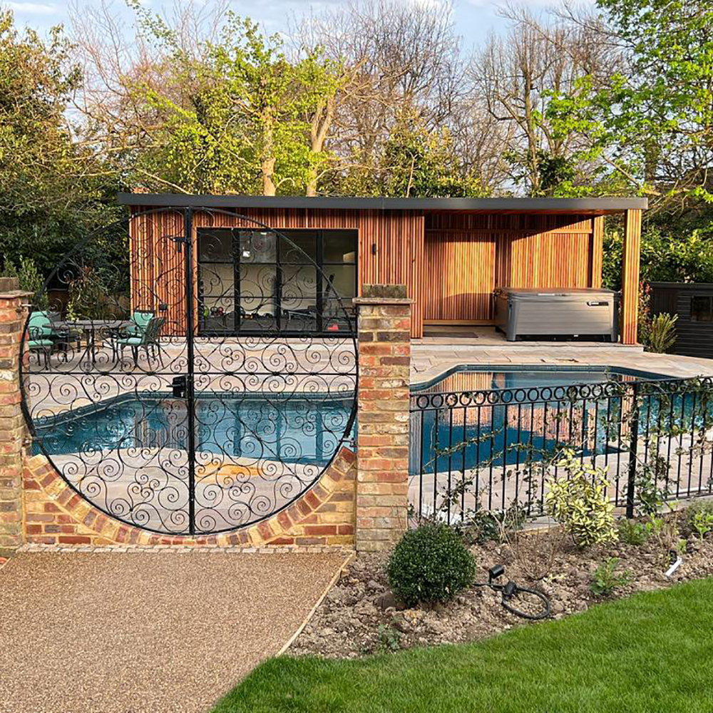 Cedar clad garden room viewed across swimming pool through landscaped garden with circular gates