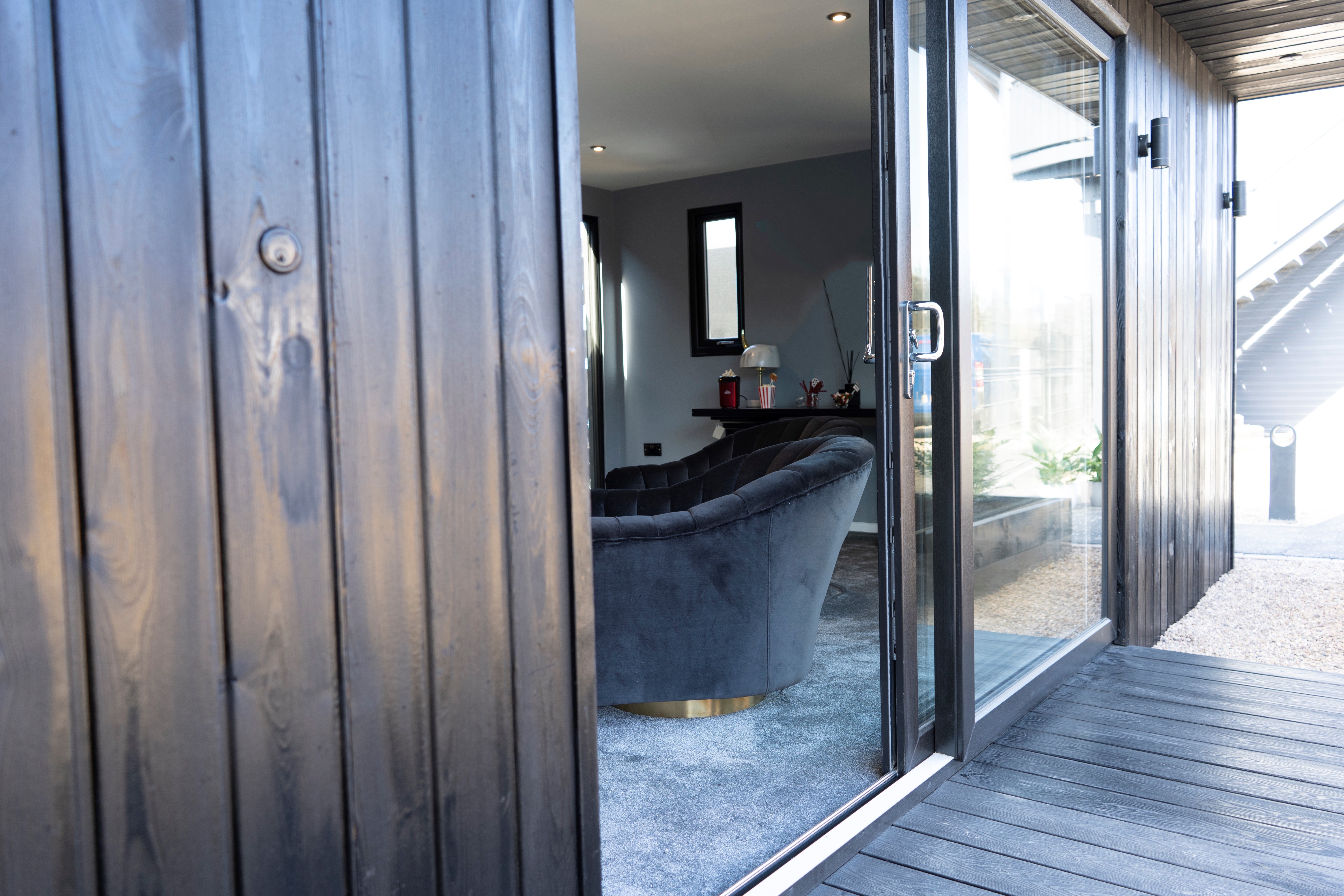 Garden room cinema exterior at dusk in Surrey with warm interior lighting visible through glazed doors