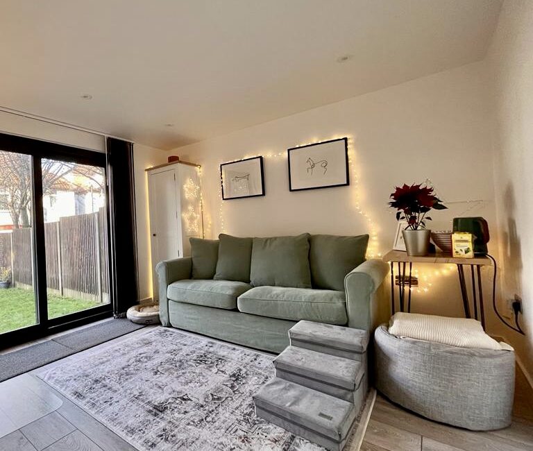 Cosy garden room interior featuring a sofa bed, with a rug on the floor and garden views through the window