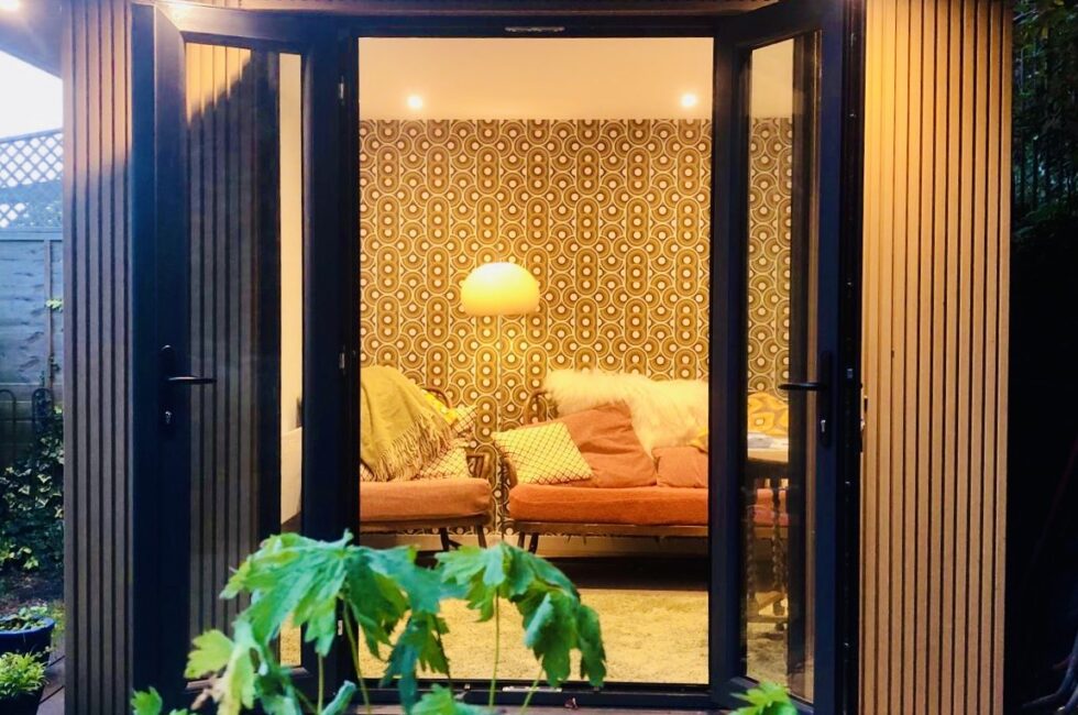 A beautifully illuminated garden room in Reigate at dusk, featuring Ecoscape natural oak cladding and stylish interior decor.