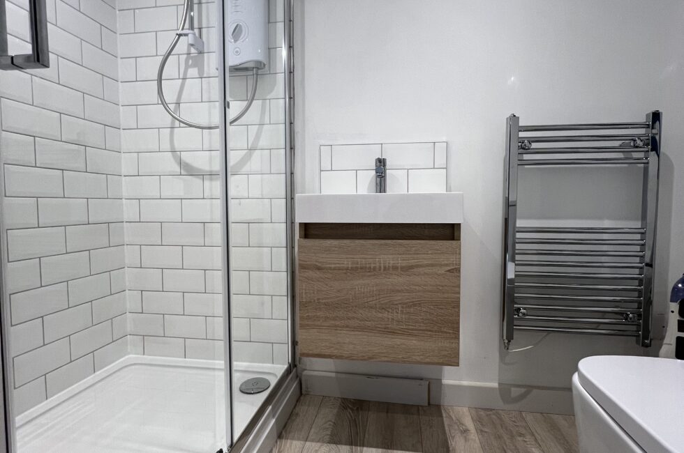 Interior of a garden room with a separate showroom featuring a toilet, sink, and towel heater.