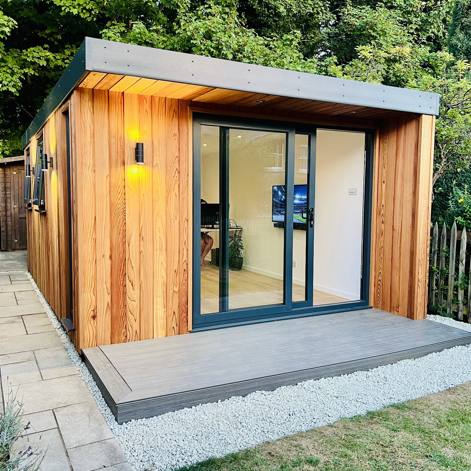 Clifton garden room in cedar cladding with roof overhang, stone steps and planted garden, Surrey