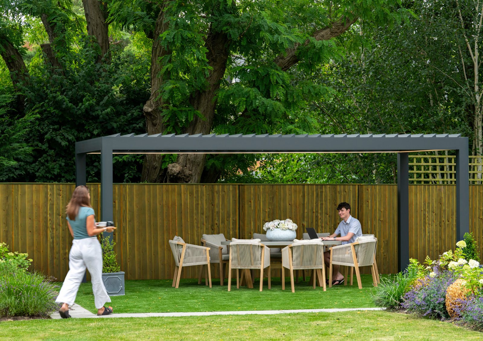 Made-to-measure louvred pergola over an outdoor dining table on a garden lawn